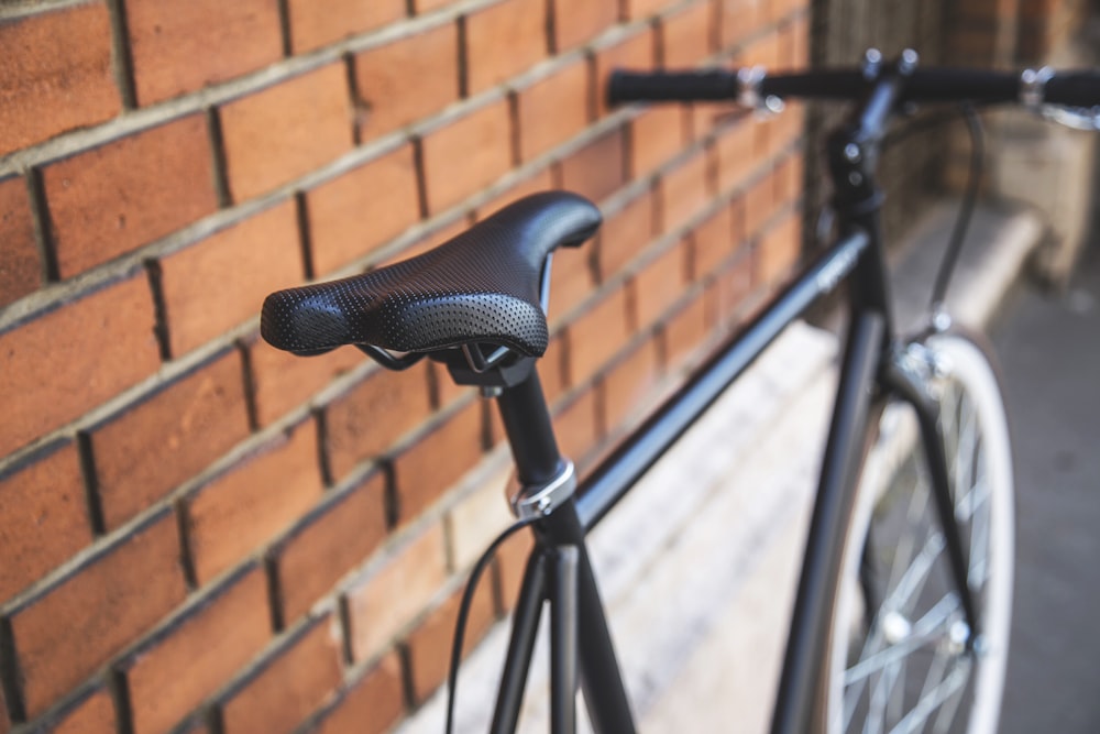 black rigid bike leaning on brown brick wall