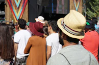 A candid shot of friends chatting and enjoying music near a decorated event stage.
