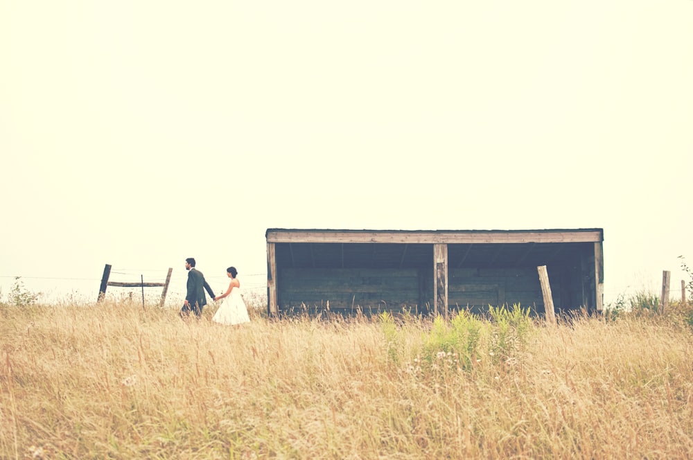 Wedding day photo in a field beside an old wooden farm building