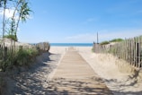 A wooden pathway leading through dunes to a quiet sandy beach at sunrise