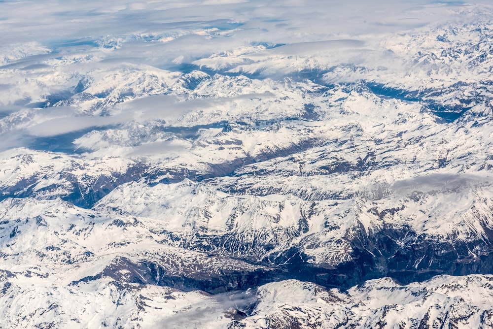 snowy mountains beside boy of water under blue sky during daytime