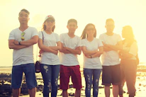 A group of friends hanging out by the beach at sunset, wearing casual streetwear with surf influences.
