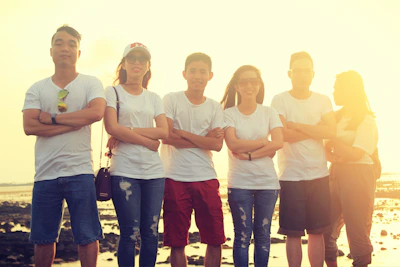 A group of friends hanging out by the beach at sunset, wearing casual streetwear with surf influences.