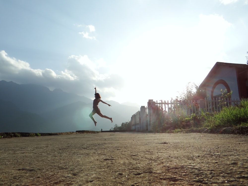 woman jumping at daytime near house