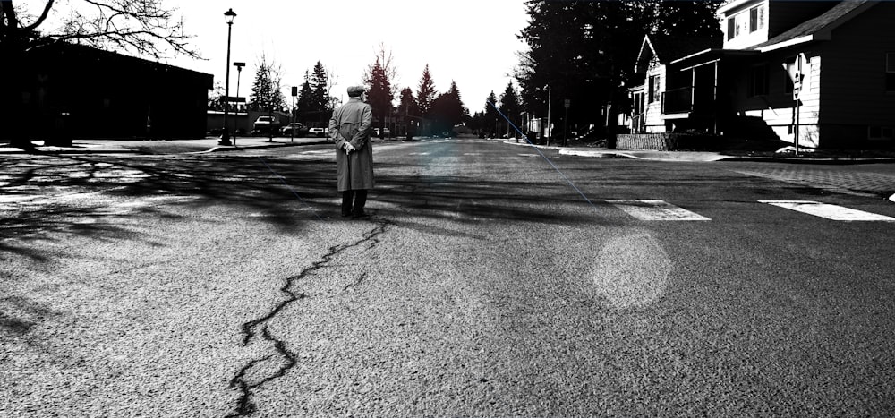 도로 한가운데에 서 있는 남자 그레이스케일 사진