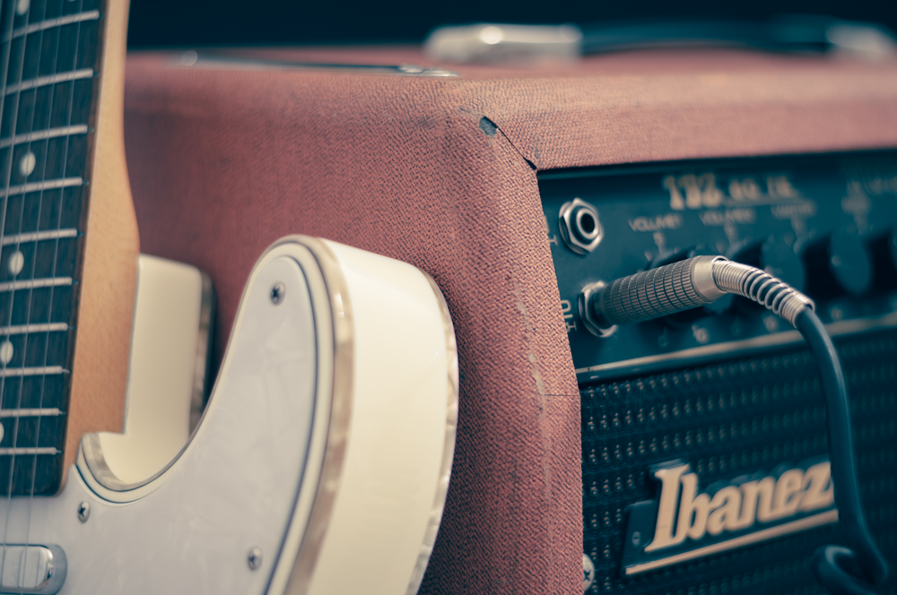 guitare électrique blanche appuyée sur un amplificateur Ibanez