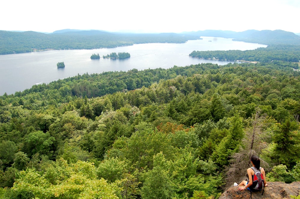 photo of woman carrying bag sitting on cliff