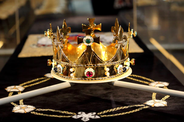 A regal crown resting atop an ancient book surrounded by symbols of the Knights Templar and Quakers.