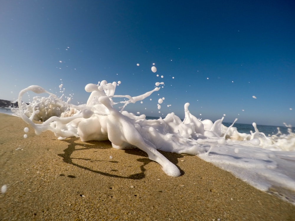 Una pequeña ola blanca cremosa aterrizando en la playa.