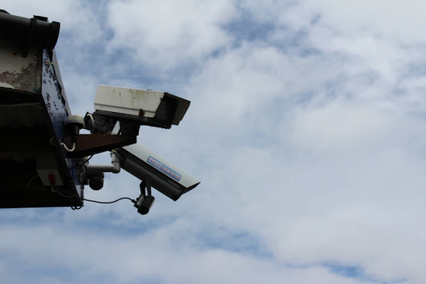 Technician installing security cameras on a commercial building exterior at sunset.