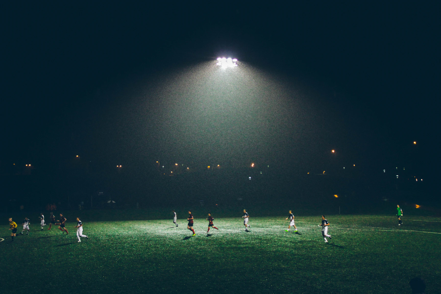A floodlit pitch at night with a match under way