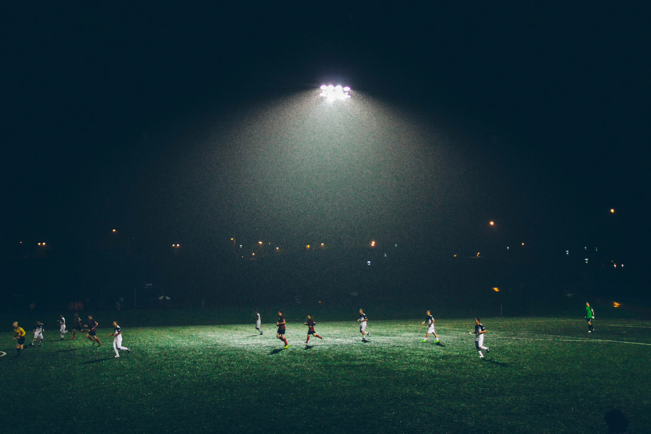 Players on a football pitch under evening lights