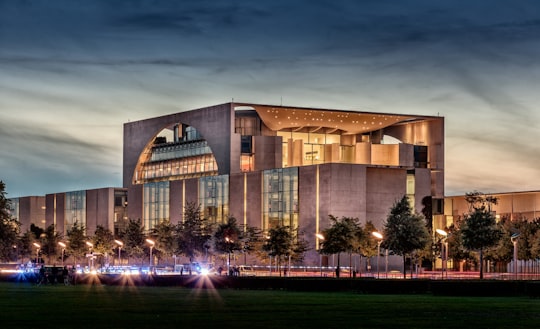 lighted concrete building under gray skies in German Chancellery Germany