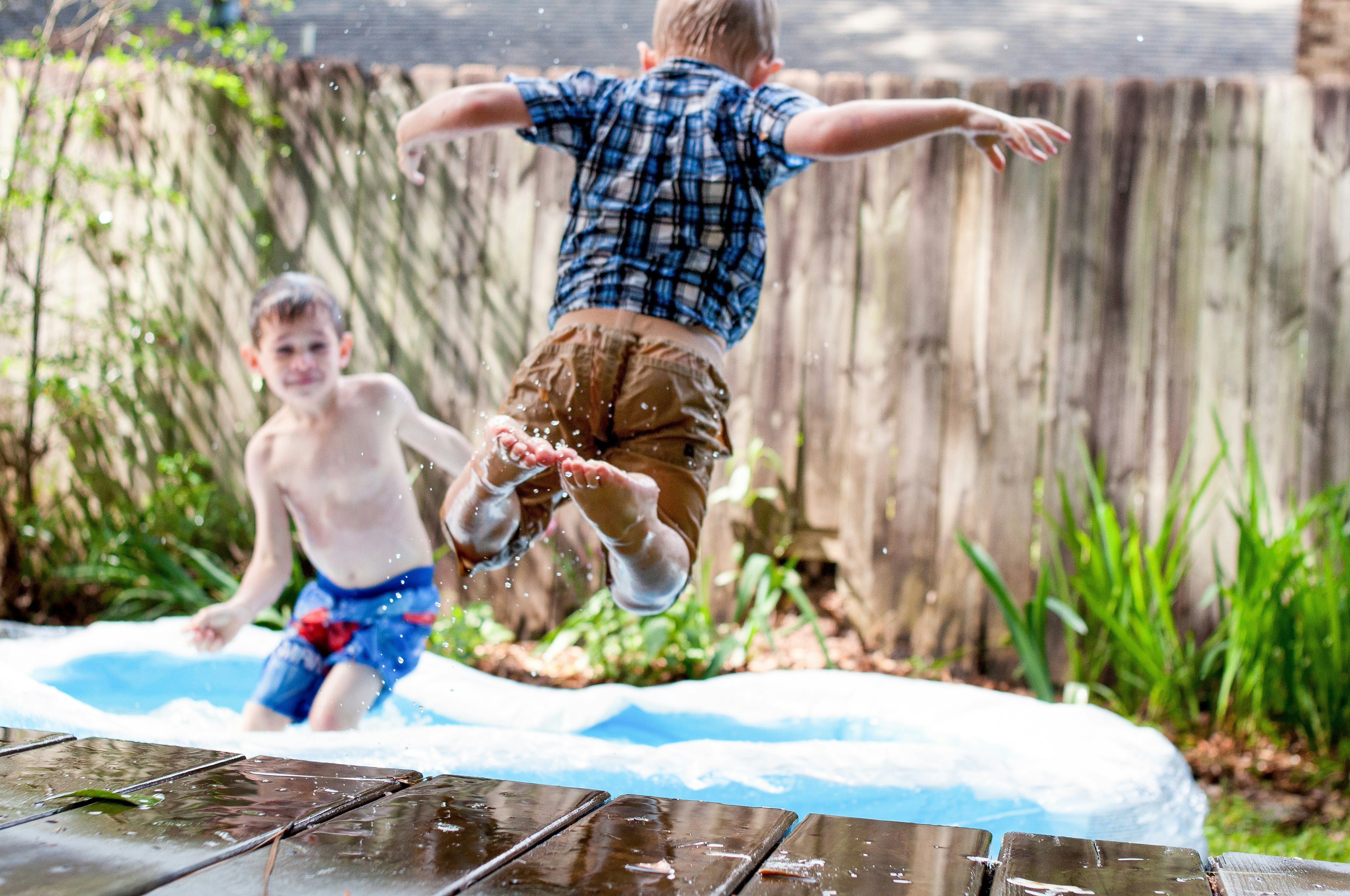 two boys playing in inflatable pool during daytime