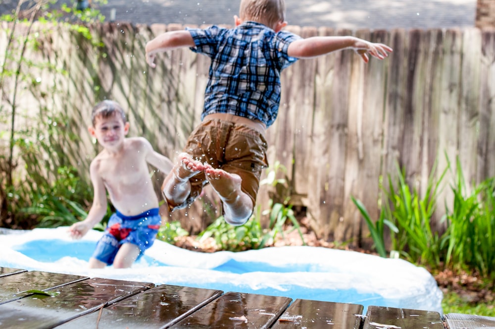 two boys playing in inflatable pool during daytime