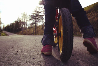 A toddler confidently balancing on a lightweight tinywheelz bike on a sunny park path.