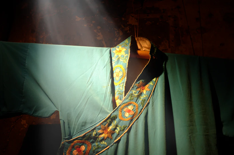 A close-up of a luxurious black thobe with intricate gold embroidery inspired by Moroccan geometry, softly illuminated against a dark background.