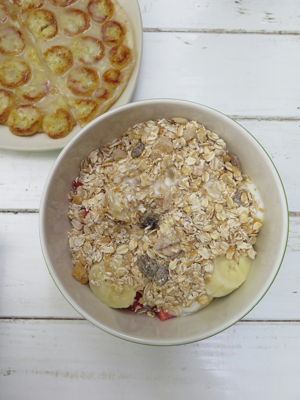 A bowl of oatmeal and a plate of bananas cooked in custard