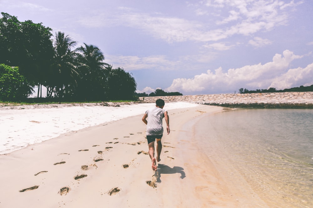 hombre con camiseta blanca corriendo en la arena