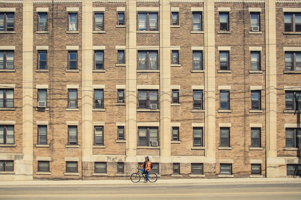 person riding bicycle near brown building