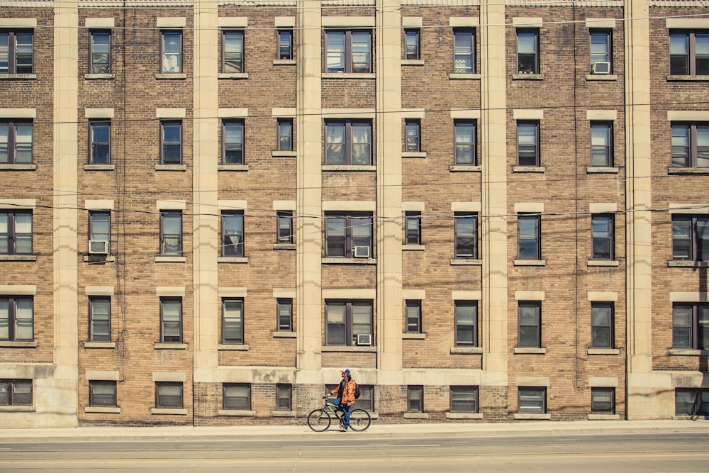 茶色の建物の近くで自転車に乗っている人