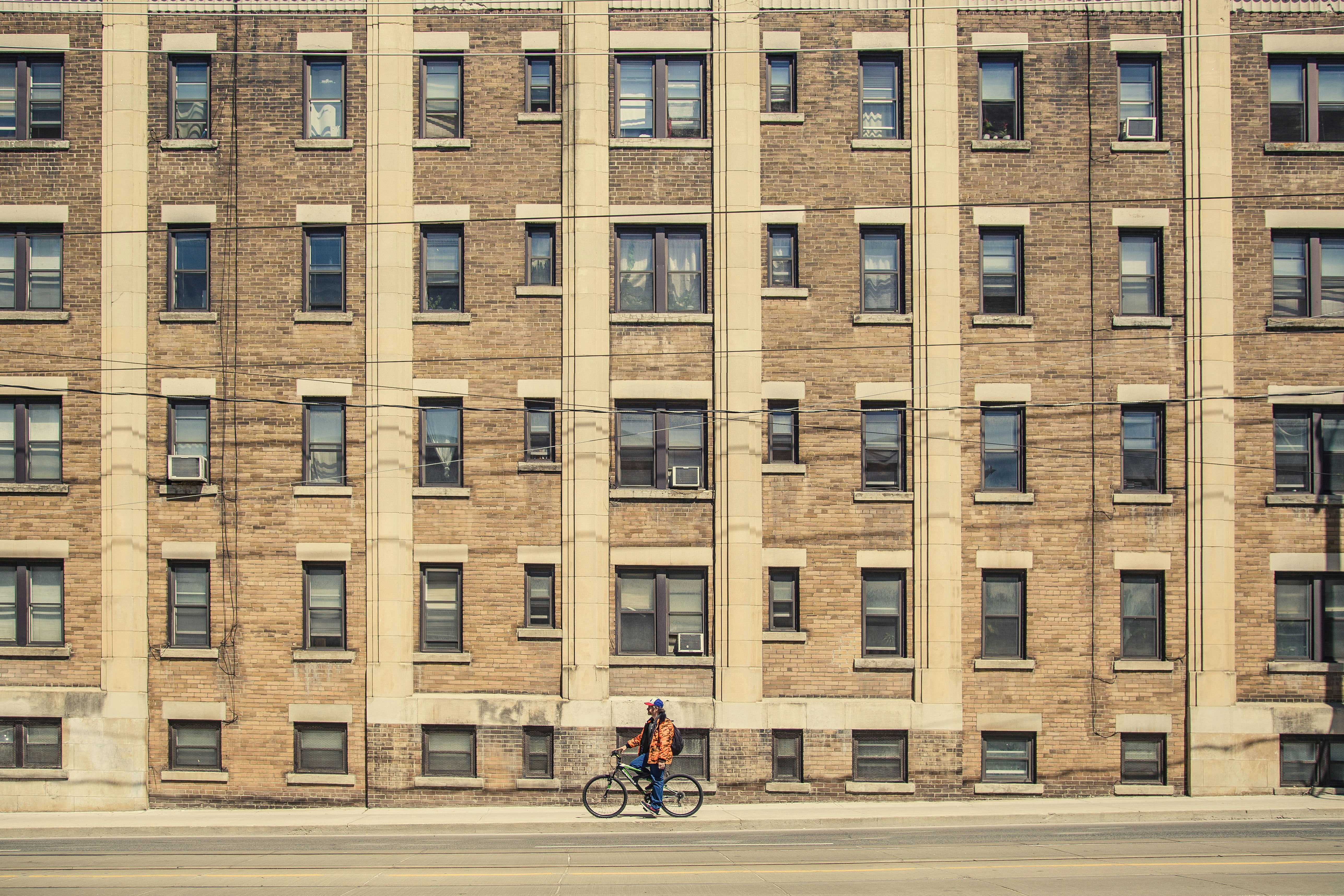 person riding bicycle near brown building
