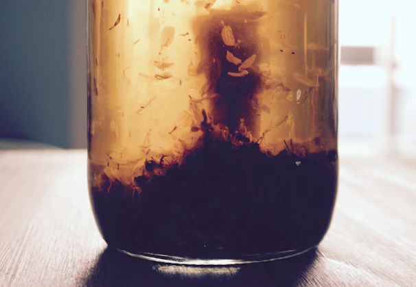 Close-up of golden ghee jars glowing softly on a rustic wooden shelf.