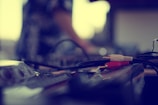 A close-up view of audio equipment with audio cables, featuring red and white connectors, laying on the surface. The background is blurred, suggesting a focus on the cables and a soft depth of field.