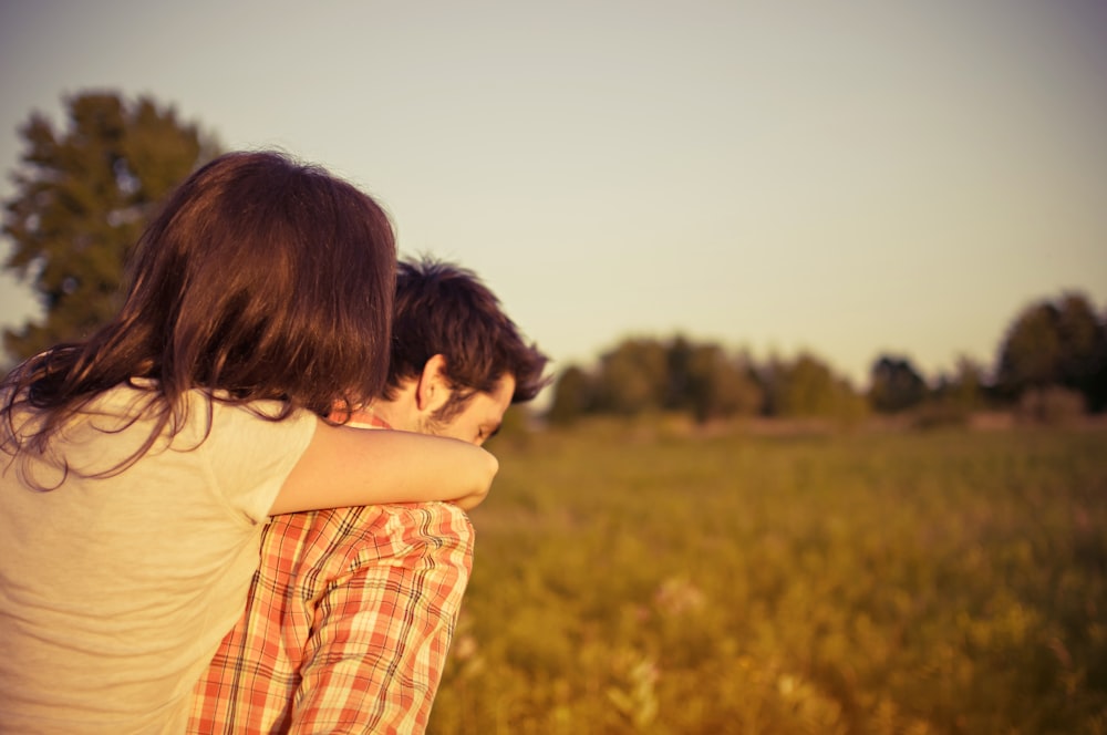 person carrying woman walking on grass field