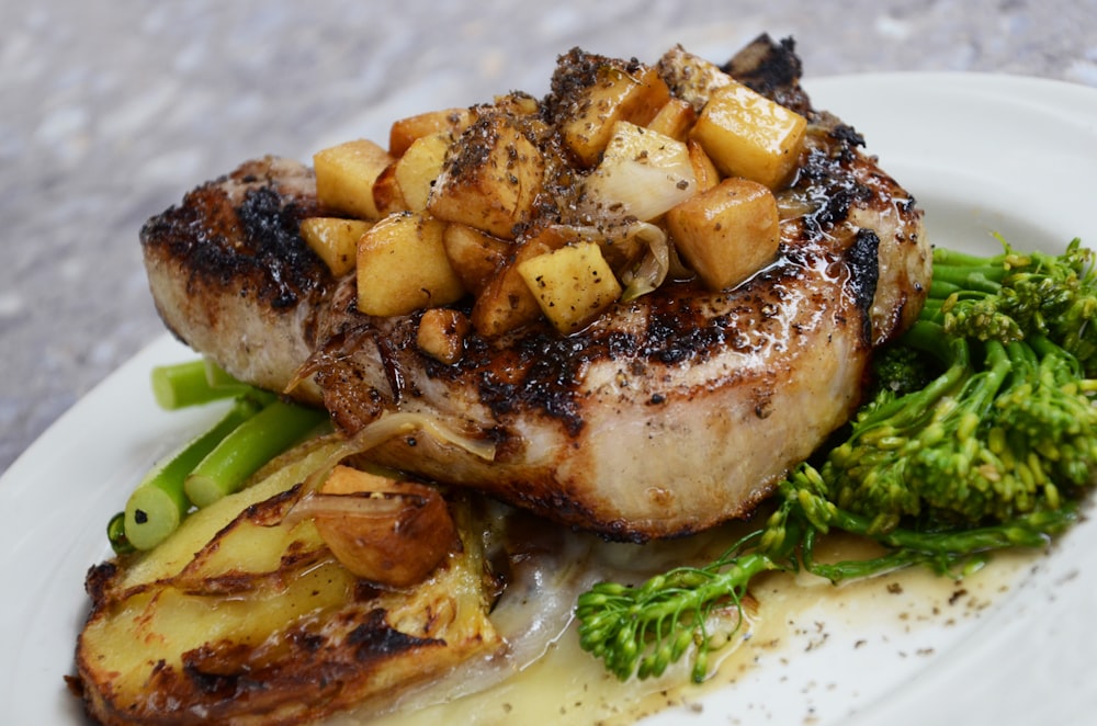 Photo Via: https://unsplash.com/photos/Yr4n8O_3UPc, Grilled pork chop with sauteed potatoes and a side of broccoli on a white plate.