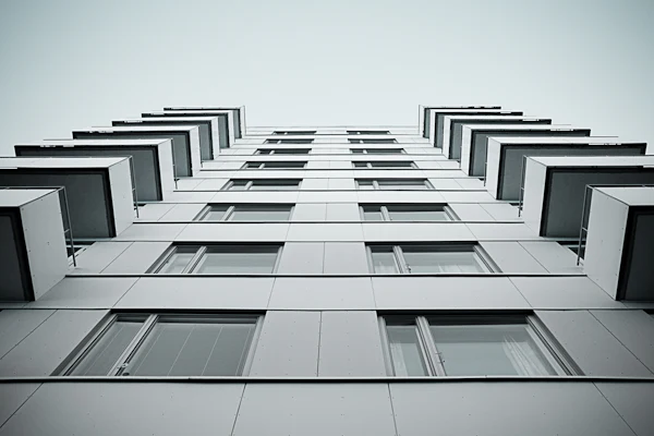 A white concrete apartment facade photographed looking straight up
