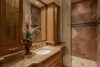 A cozy bathroom featuring white shaker-style cabinets under a marble countertop.