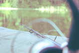 Close-up of a high-quality fishing rod resting beside a tranquil riverbank at dawn.
