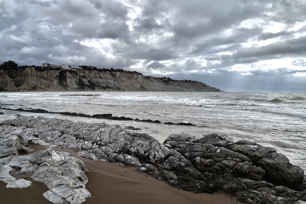 grey rocks near sea under grey sky