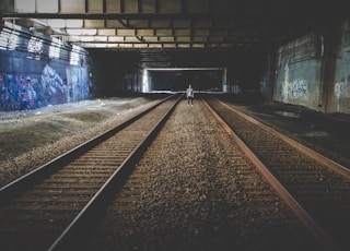 person standing in the middle of train rail tracks