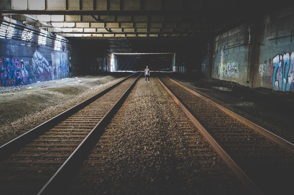 person standing in the middle of train rail tracks