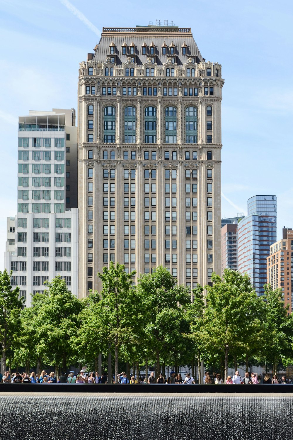 white and gray concrete building with glass windows and green trees on front