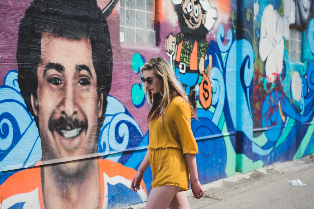 woman walking beside wall with graffiti