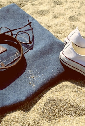 pair of white low-top sneakers on brown sand