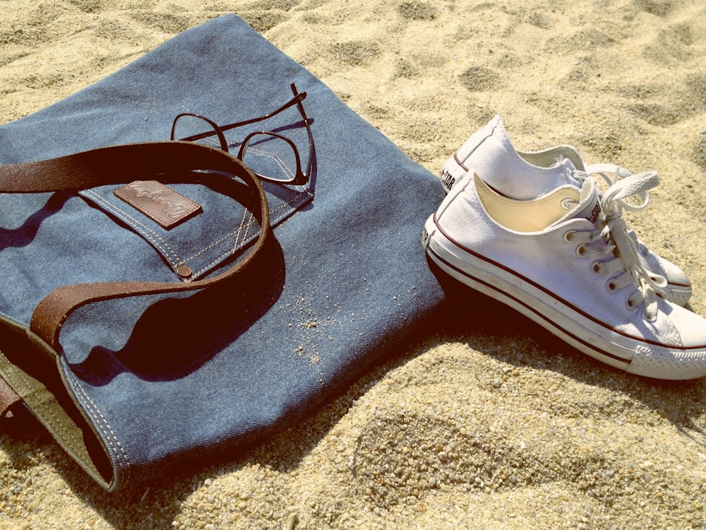 Paar weiße Low-Top-Sneaker auf braunem Sand
