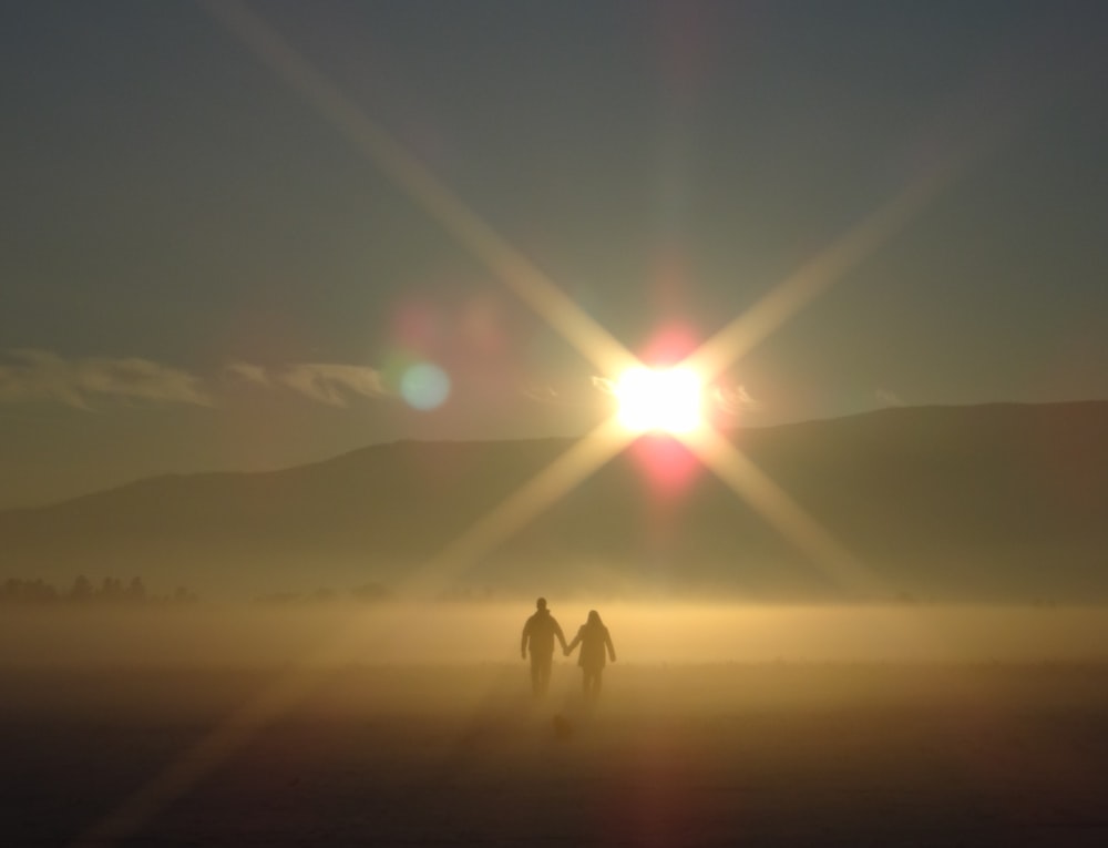 man and woman holding hands walking through the mountain