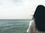 woman facing body of water under cloudy sky