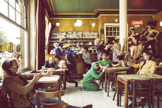 A lively group of Pee-Wee Herman fans dressed in colorful costumes, laughing and holding drinks at a Portland pub.