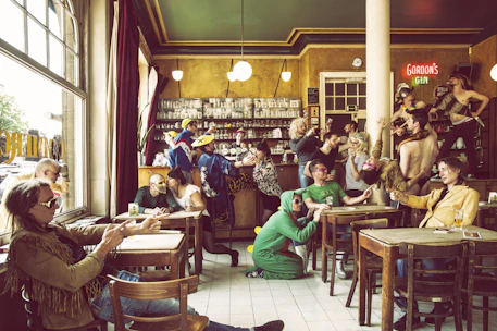 A lively group of Pee-Wee Herman fans dressed in colorful costumes, laughing and holding drinks at a Portland pub.
