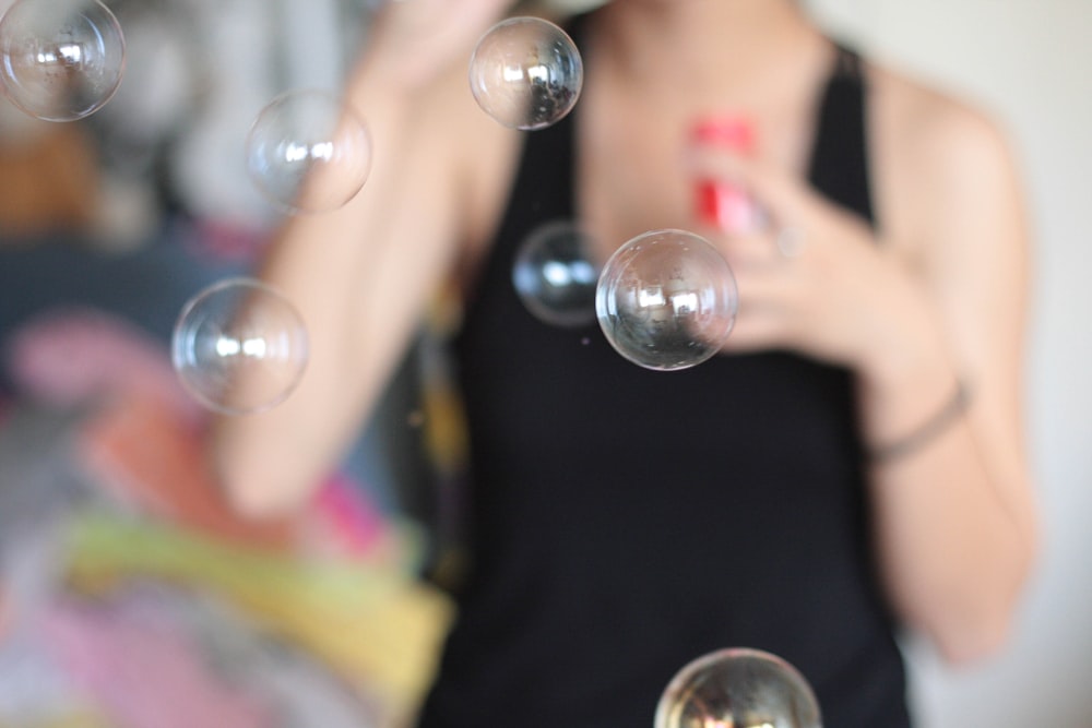 Foto de enfoque selectivo de burbujas sopladas por una persona que lleva una camiseta sin mangas negra