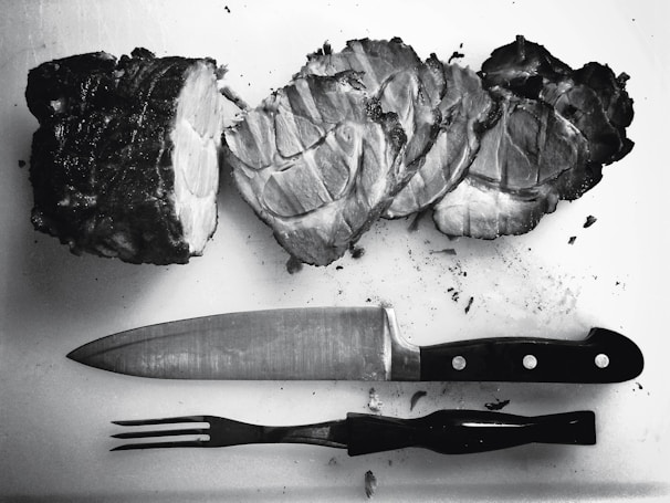 A kamsu llc carving knife cutting tender roast meat, highlighting the sharp blade.