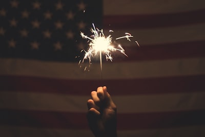 person holding sparkler 4th of july teams background