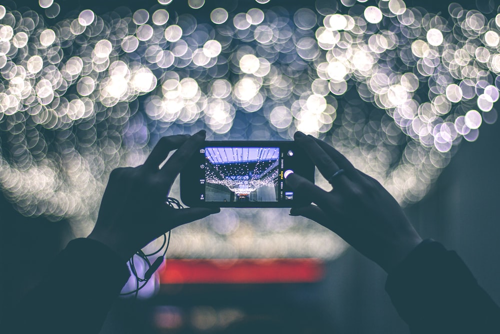 Selektive Fokusfotografie einer Person, die ein Smartphone in der Hand hält, während sie die Landschaft fotografiert