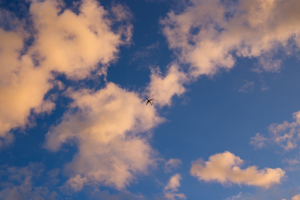 Silhouette eines Flugzeugs, das tagsüber unter weißem und blauem Himmel fliegt