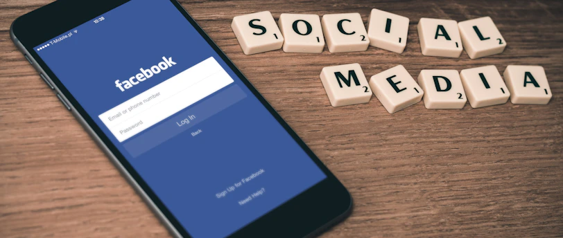 space gray iPhone 6 with Facebook log-in display near Social Media scrabble tiles